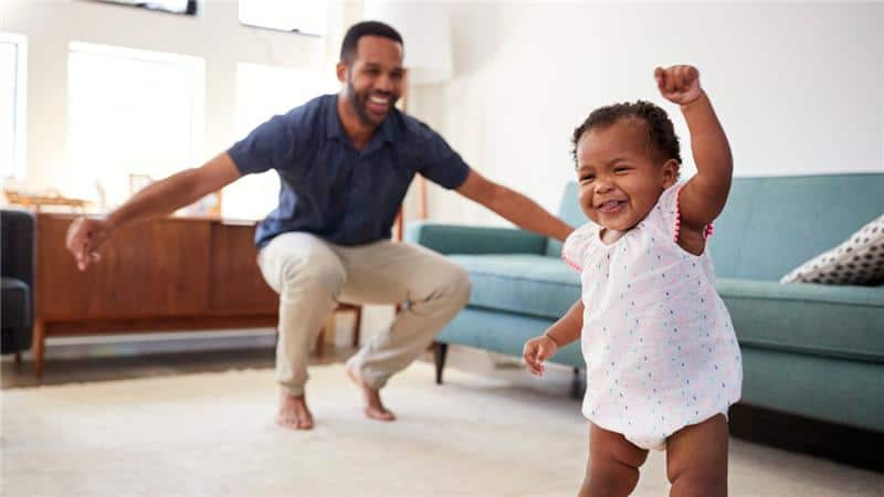 Father and toddler smiling while dancing